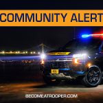 Graphic titled “Community Alert” featuring a Delaware State Police SUV with flashing red and blue lights parked at night near a lit suspension bridge. A silhouette map of Delaware appears on the left, the text “BecomeATrooper.com” on the bottom center, and social media icons are shown at the bottom right corner.