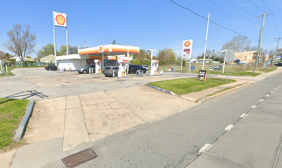 Shell gas station at 3001 New Castle Avenue in New Castle, Delaware, showing a small convenience store, multiple fuel pumps under a canopy, parked vehicles, and roadside signage along a two-lane street during daytime.